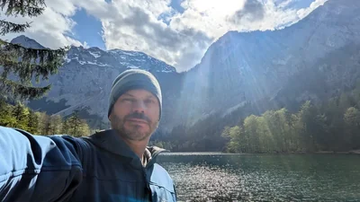 Felipe beside a lake surrounded by mountains in Austria.